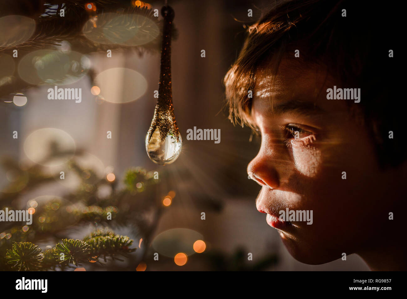 Ragazzo che guarda ad un ornamento di cristallo appeso a un albero di Natale Foto Stock