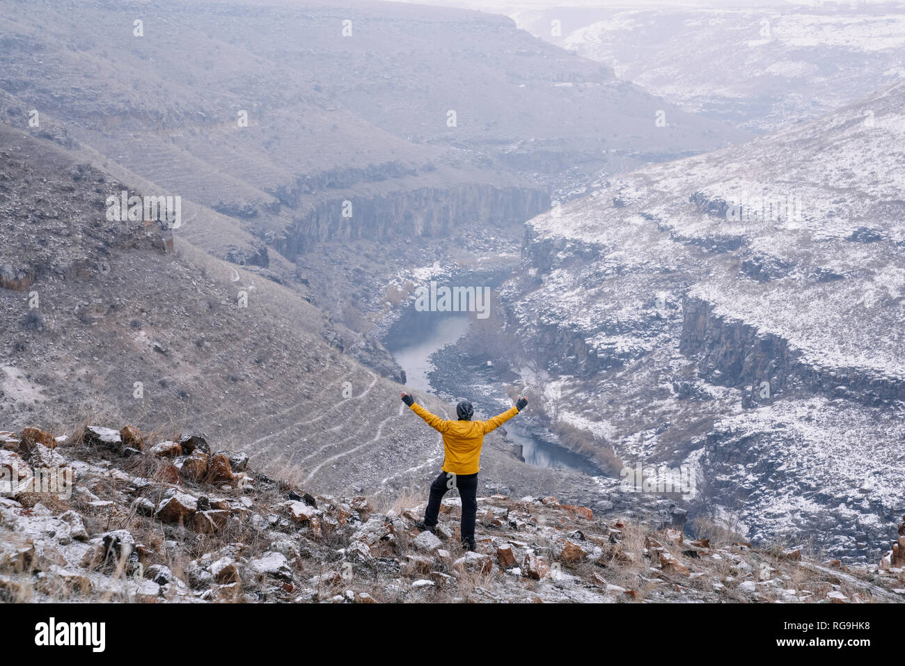 Escursionista con rivestimento giallo permanente sulla cima di una montagna e godere. Foto Stock