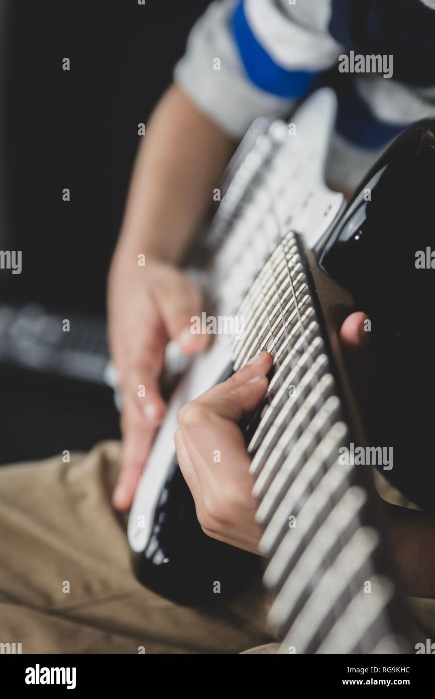 8 anno di età Inglesi Indian boy praticando la chitarra a casa. Foto Stock