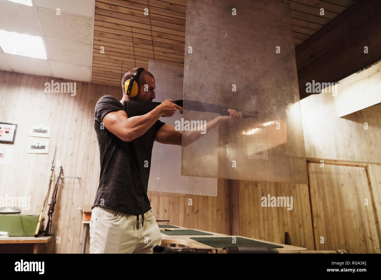 Uomo che ha di mira con un fucile in una piscina poligono di tiro Foto Stock