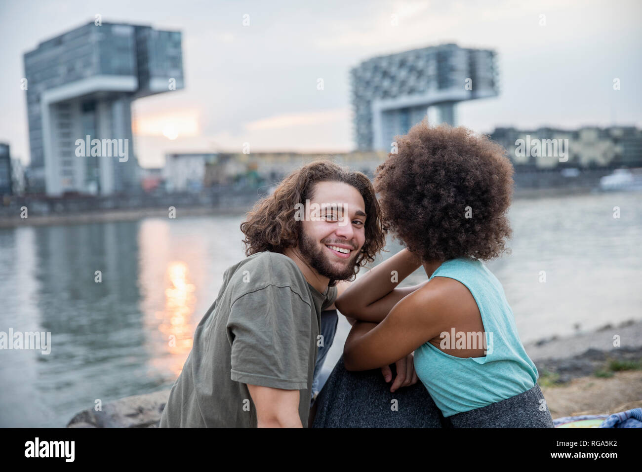 Germania, Colonia, felice coppia rilassante in riva al fiume e al tramonto Foto Stock