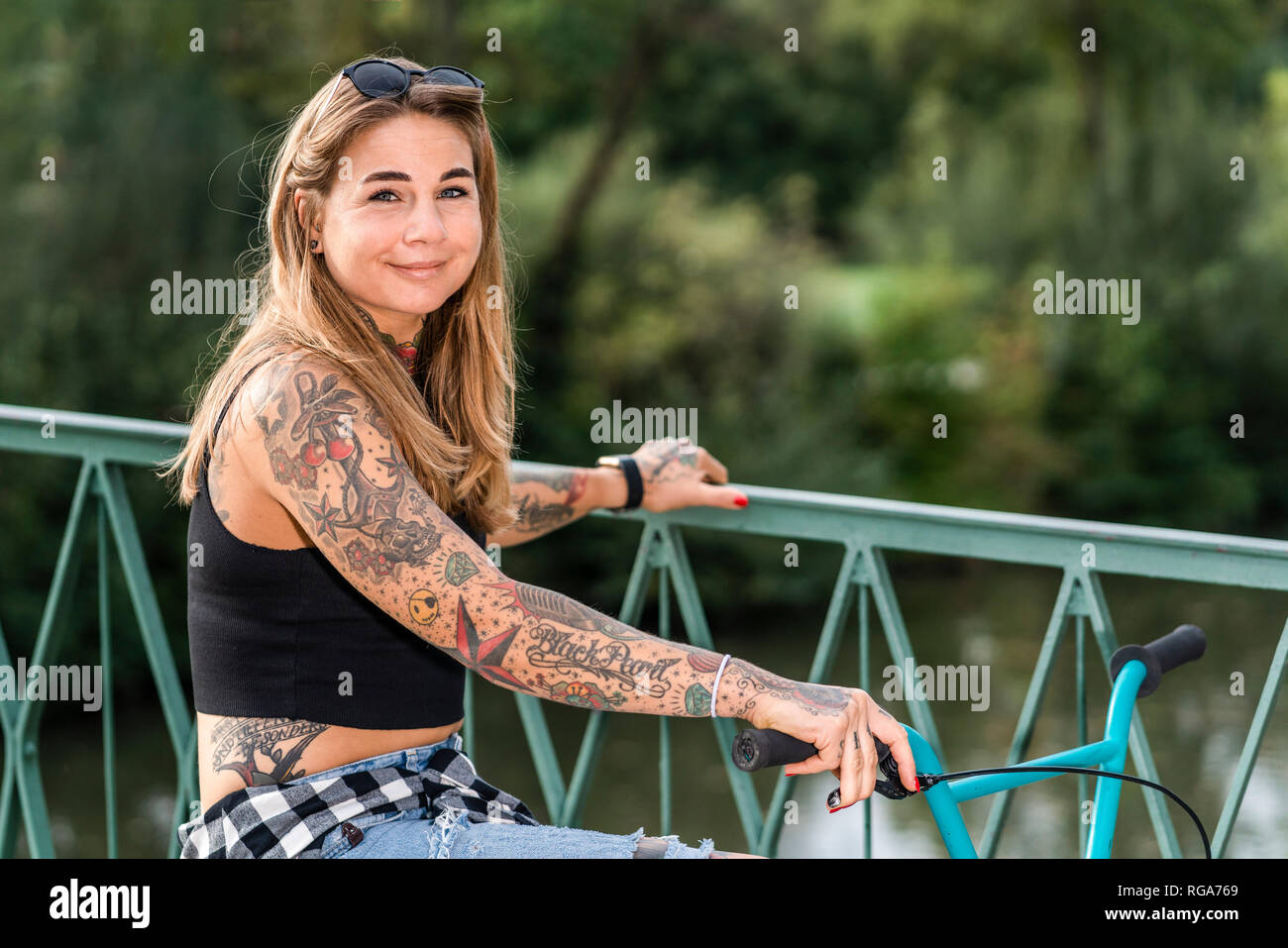 Ritratto di una donna tatuata con una bici Foto Stock
