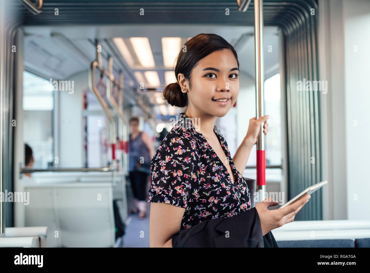 Sorridente studente asiatico il pendolarismo per lavorare su un treno Foto Stock