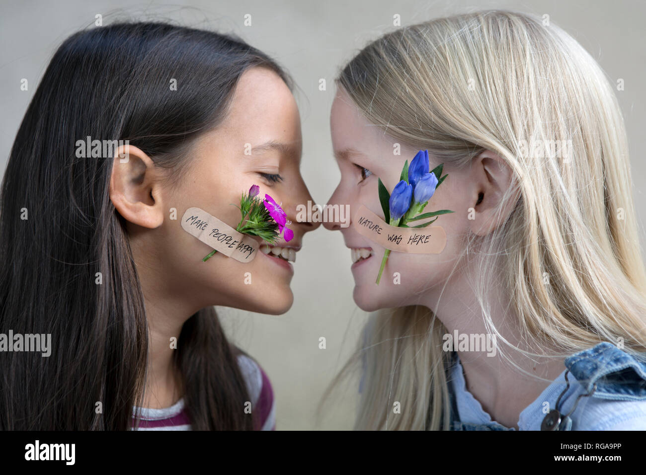 Profili di due ragazze sorridenti con le teste dei fiori sulle loro guance Foto Stock