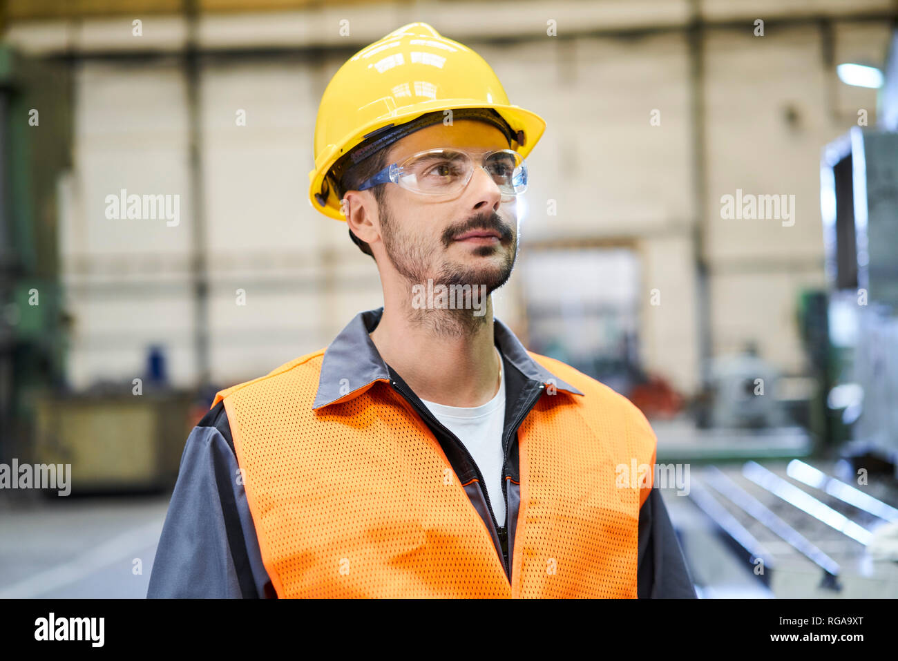 Uomo che indossa indumenti da lavoro protettiva guardando intorno in fabbrica Foto Stock