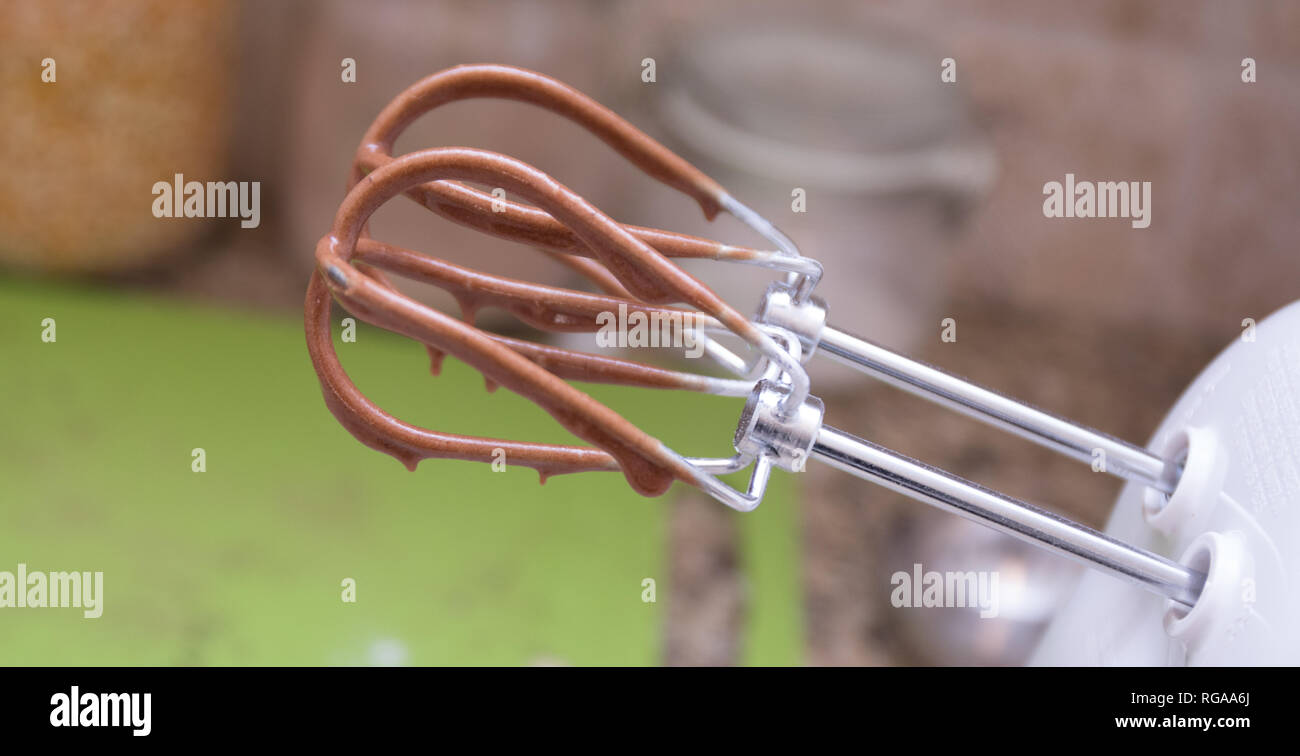 Fruste su un mixer elettrico il gocciolamento con torta al cioccolato della pastella. Foto Stock