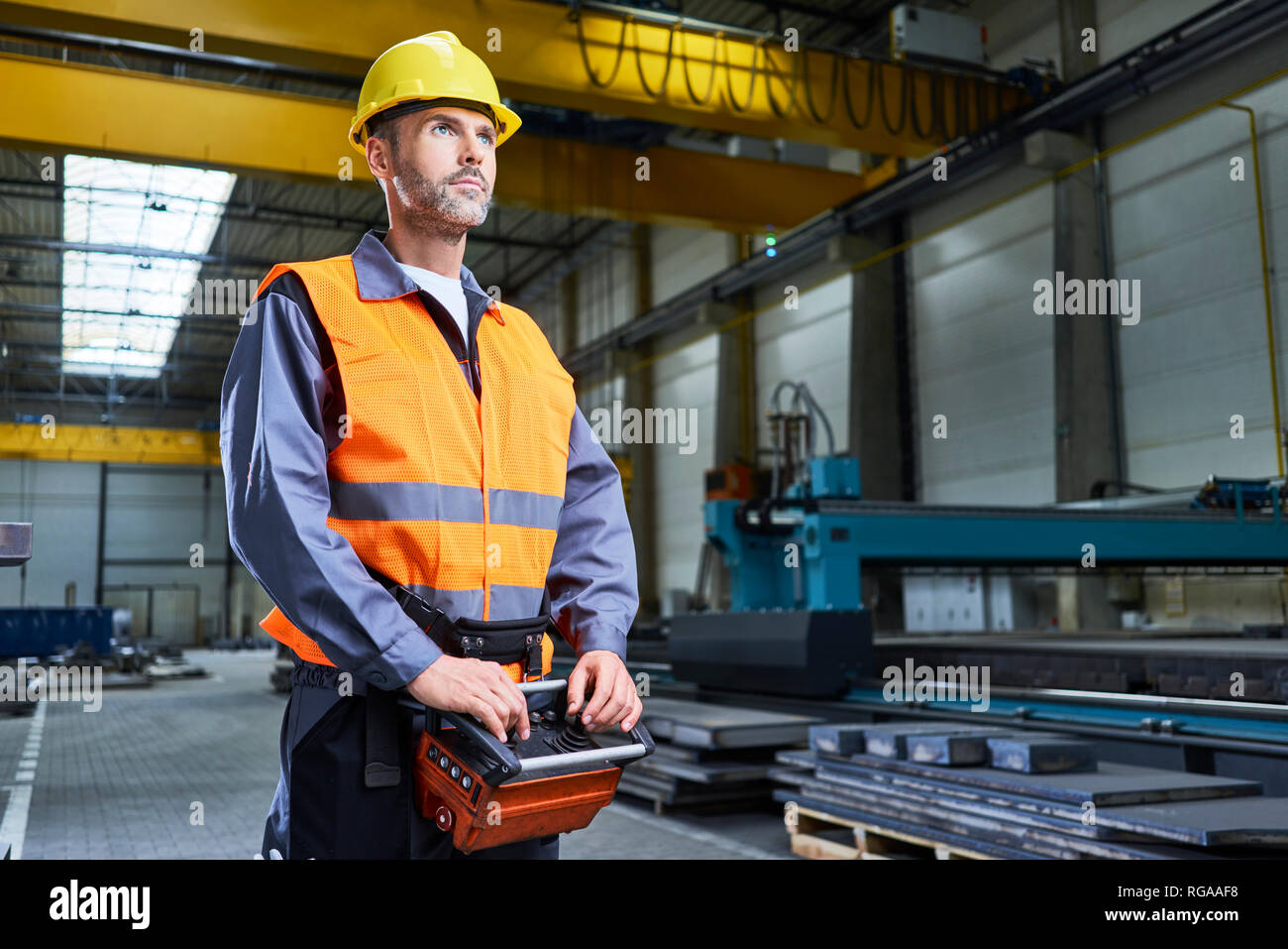 Ritratto di uomo in fabbrica macchine operative con la console remota Foto Stock