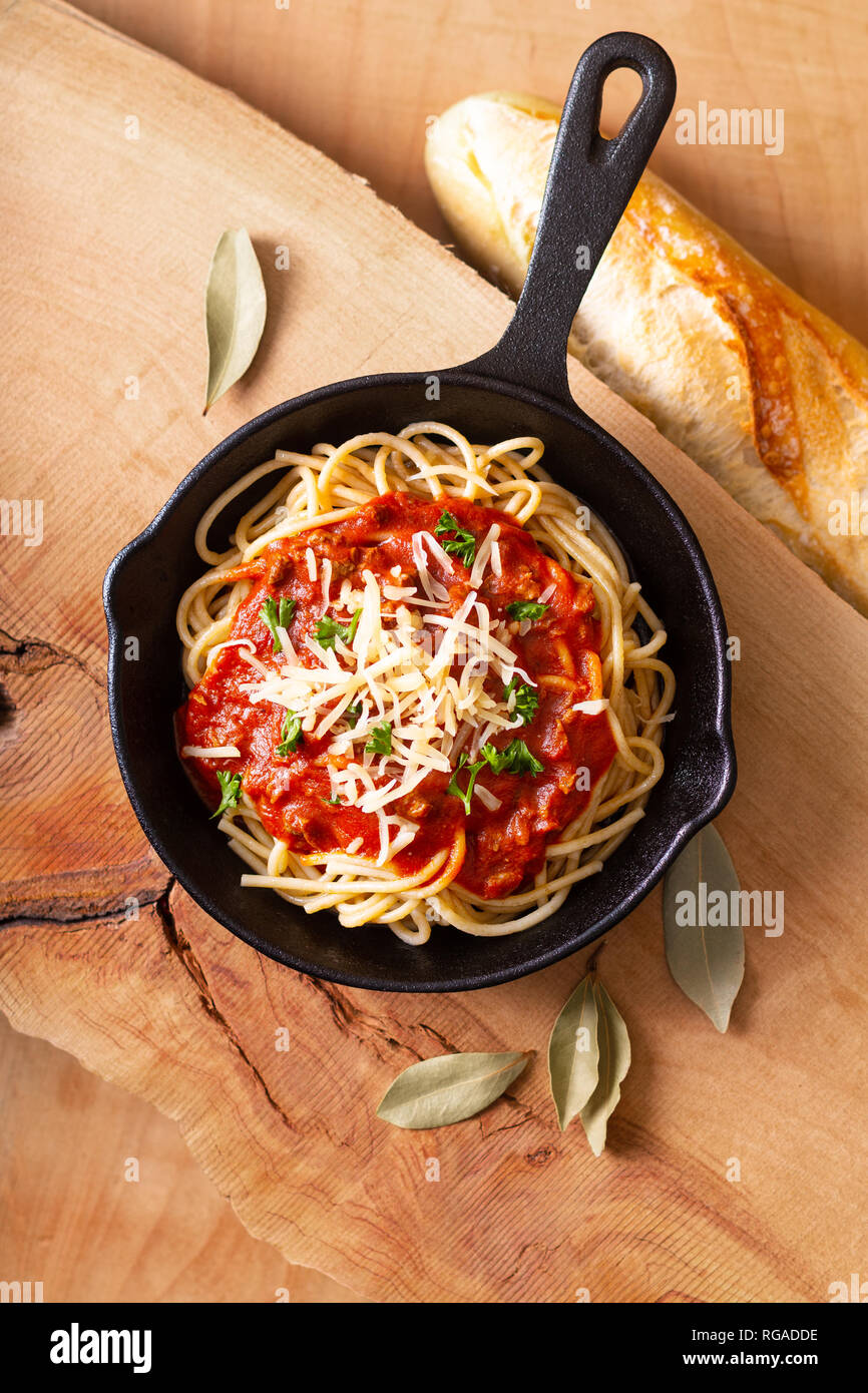 Concetto di cibo in casa spaghetti alla bolognese in ghisa su legno blackground Foto Stock