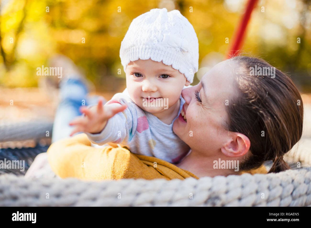 Ritratto di bambina rilassante con sua madre su altalena in autunno Foto Stock