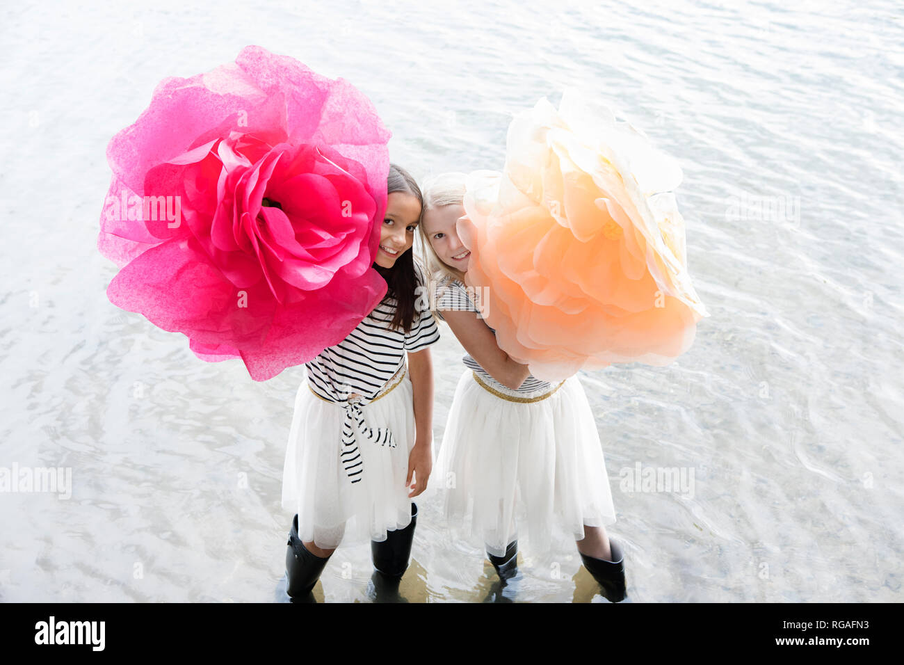 Due ragazze in piedi in un lago con due grandi fiori artificiali Foto Stock