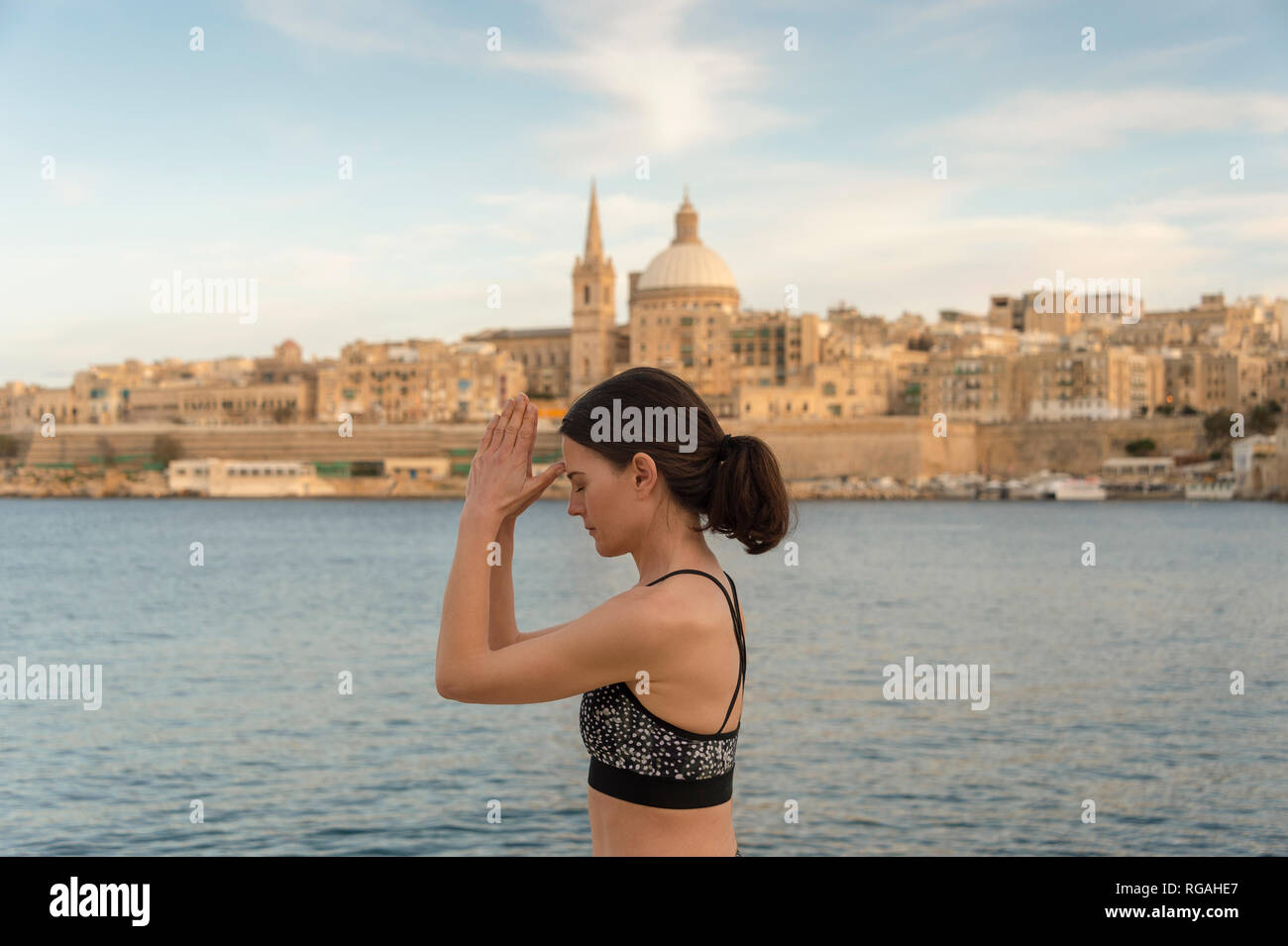 Donna spirituale nella meditazione yoga terzo occhio posano con la Valletta cityscape sfondo Foto Stock
