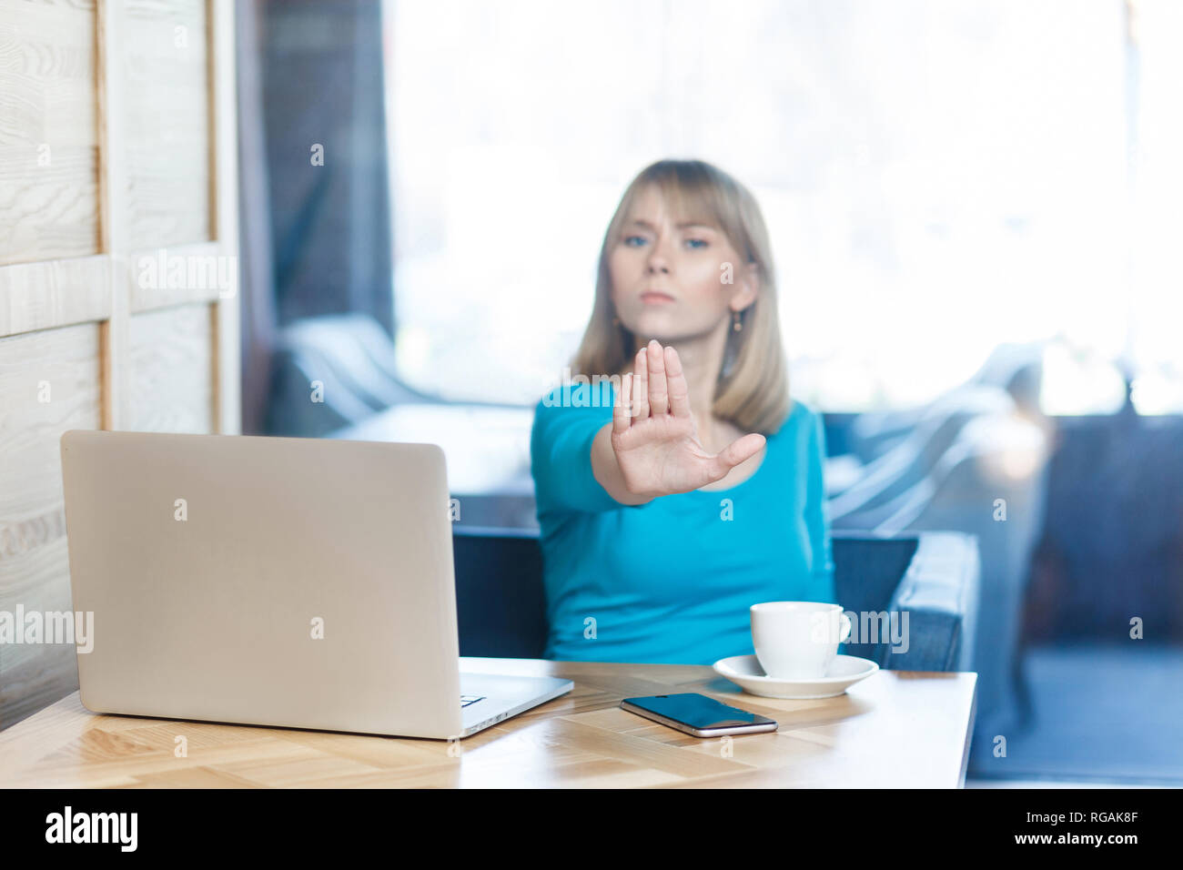 Smettere di farlo! Ritratto di aggressivo infelice fanciulla freelancer con capelli biondi in camicetta blu sono seduti in cafe e di cattivo umore e si prega di Foto Stock