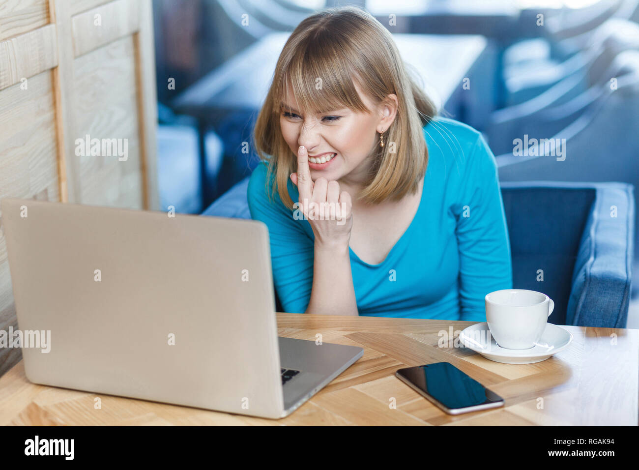 Siete bugiardo. Ritratto di Angry Young girl freelancer con capelli biondi in blu t-shirt sono seduti in cafe e rendendo la chiamata video su laptop, parlando ab Foto Stock