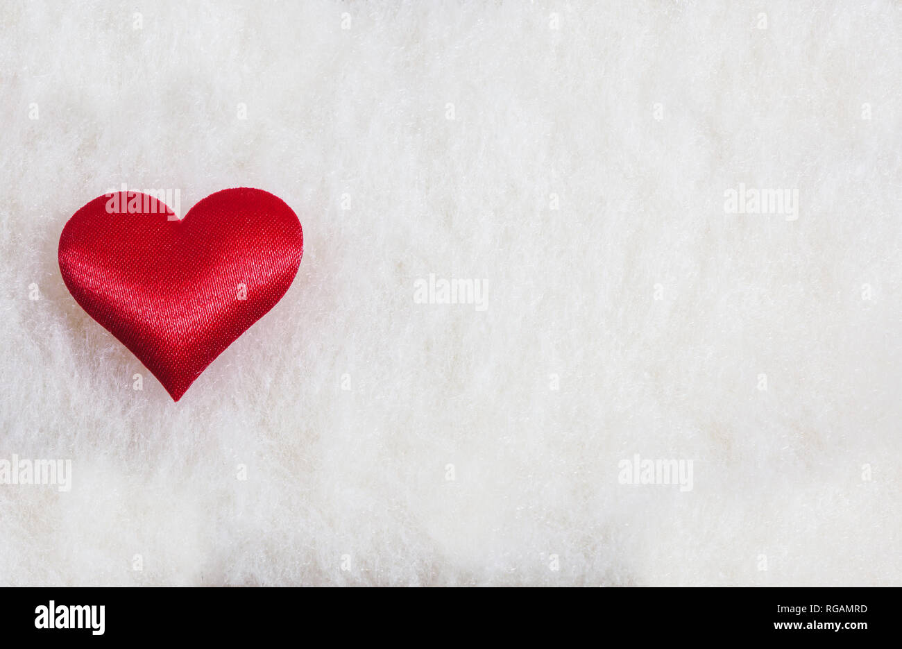 Adorabili unico cuore rosso in un fuzzy e soffice sfondo bianco. Il giorno di San Valentino o concetto romantico, con copia spazio. Foto Stock