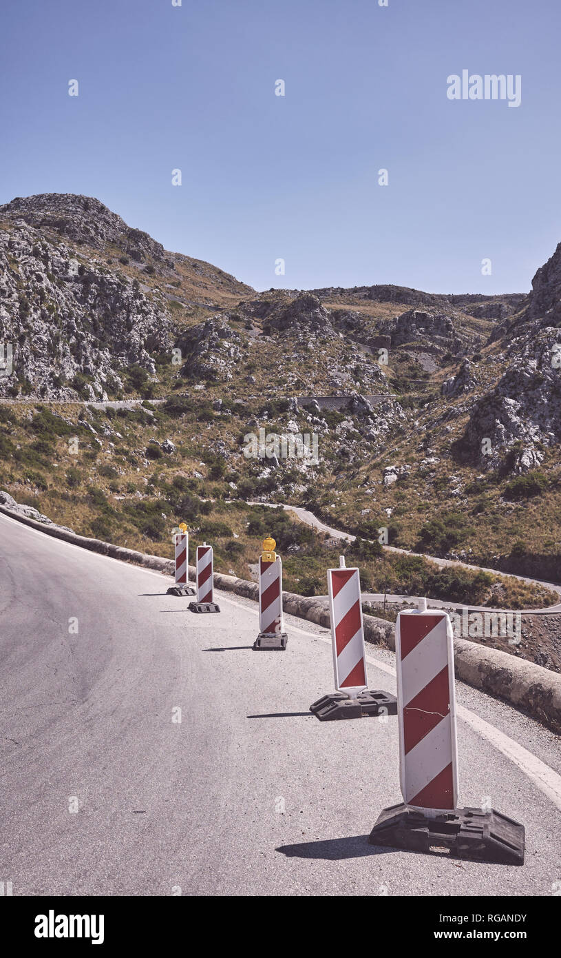 Avvolgimento di montagna su strada portatile con attenzione i cartelli stradali, dai toni di colore dell'immagine. Foto Stock