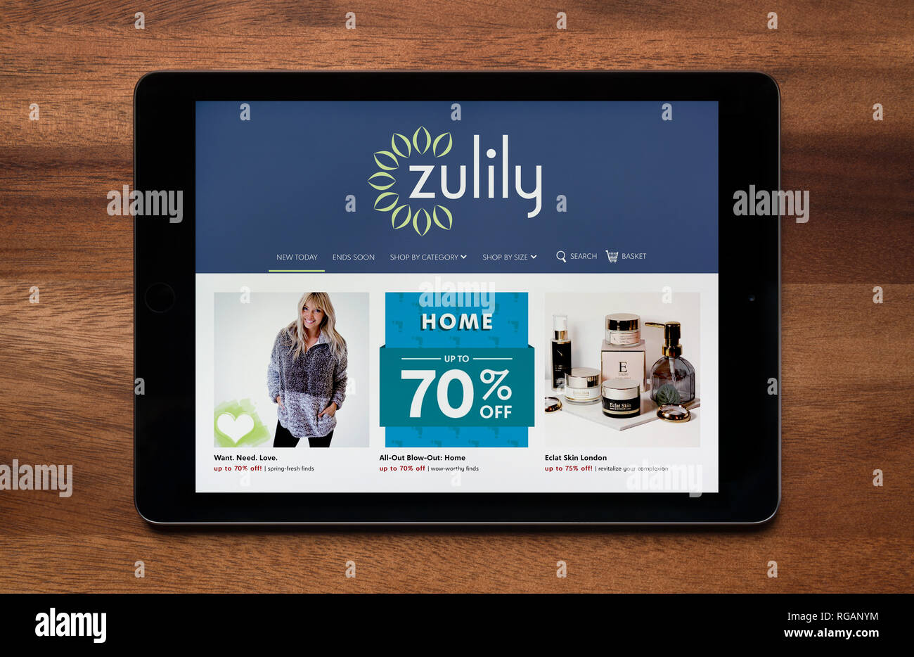 Il sito web di Zulily è visto su un tablet iPad, il quale è appoggiato su un tavolo di legno (solo uso editoriale). Foto Stock