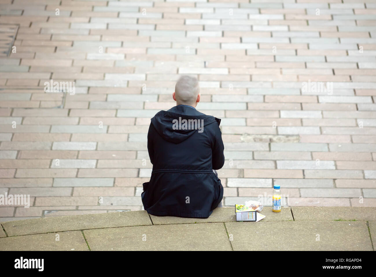 Il giovane studente di sesso maschile con un pranzo di trattare il sandwich e un drink seduti sui gradini Glasgow, Scotland, Regno Unito Foto Stock