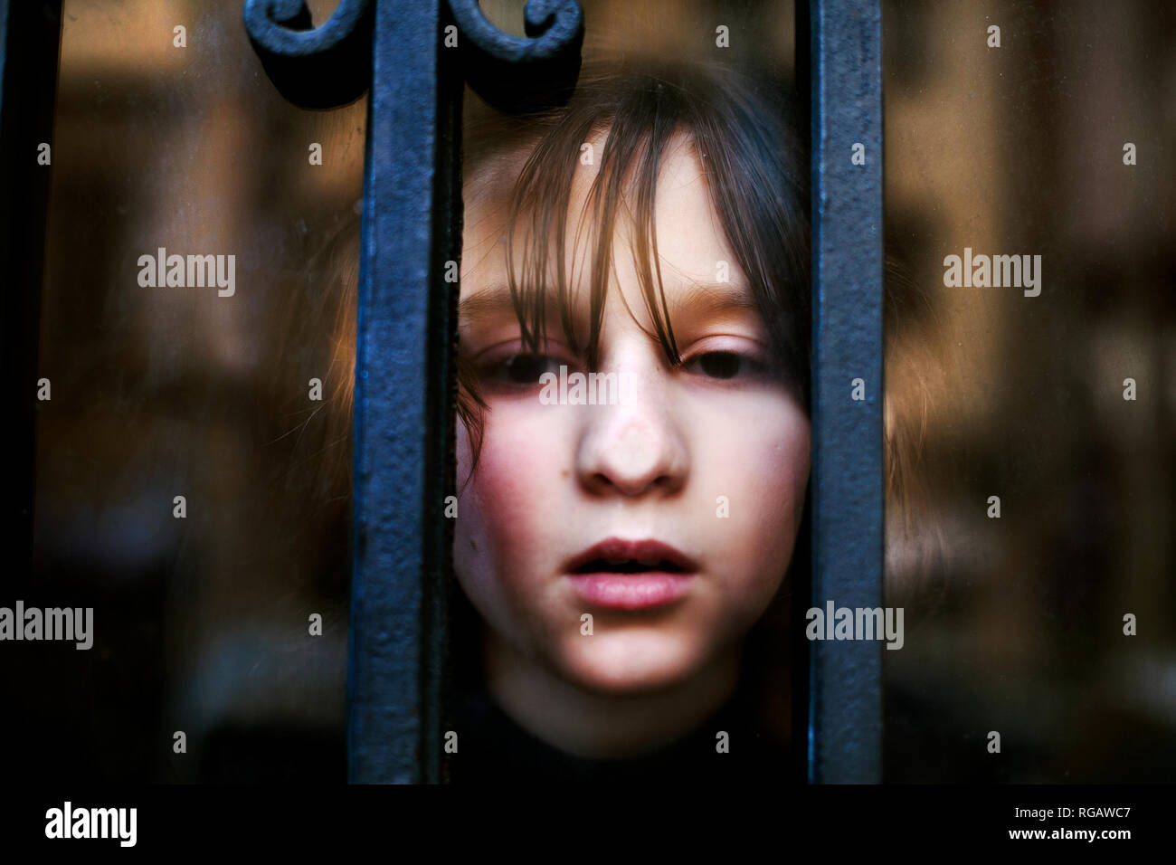 Ragazzo con la faccia premuta contro il vetro di una porta anteriore. Foto Stock