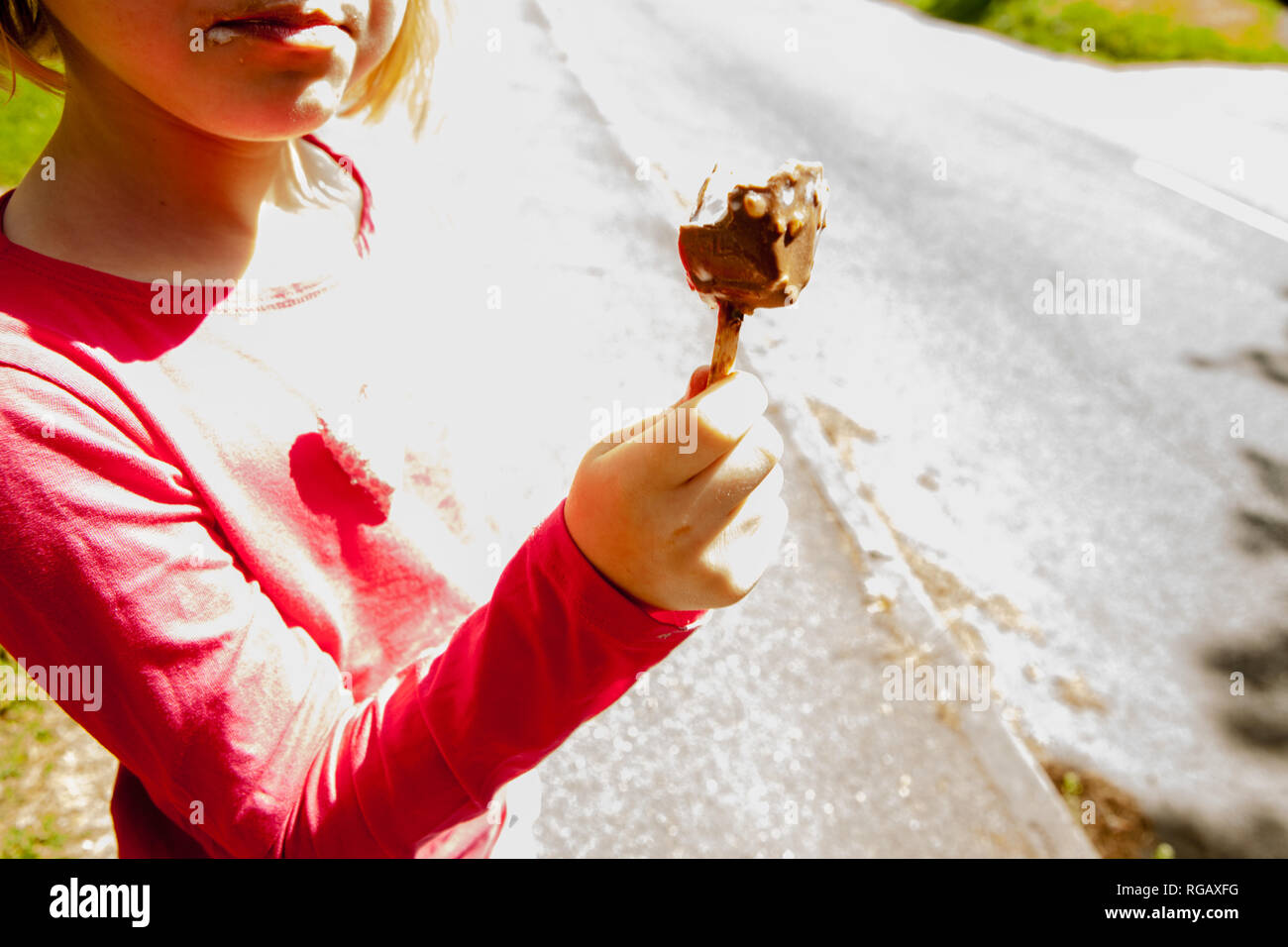 Ragazza giovane con ricoperta di cioccolato gelato su un bastone Foto Stock