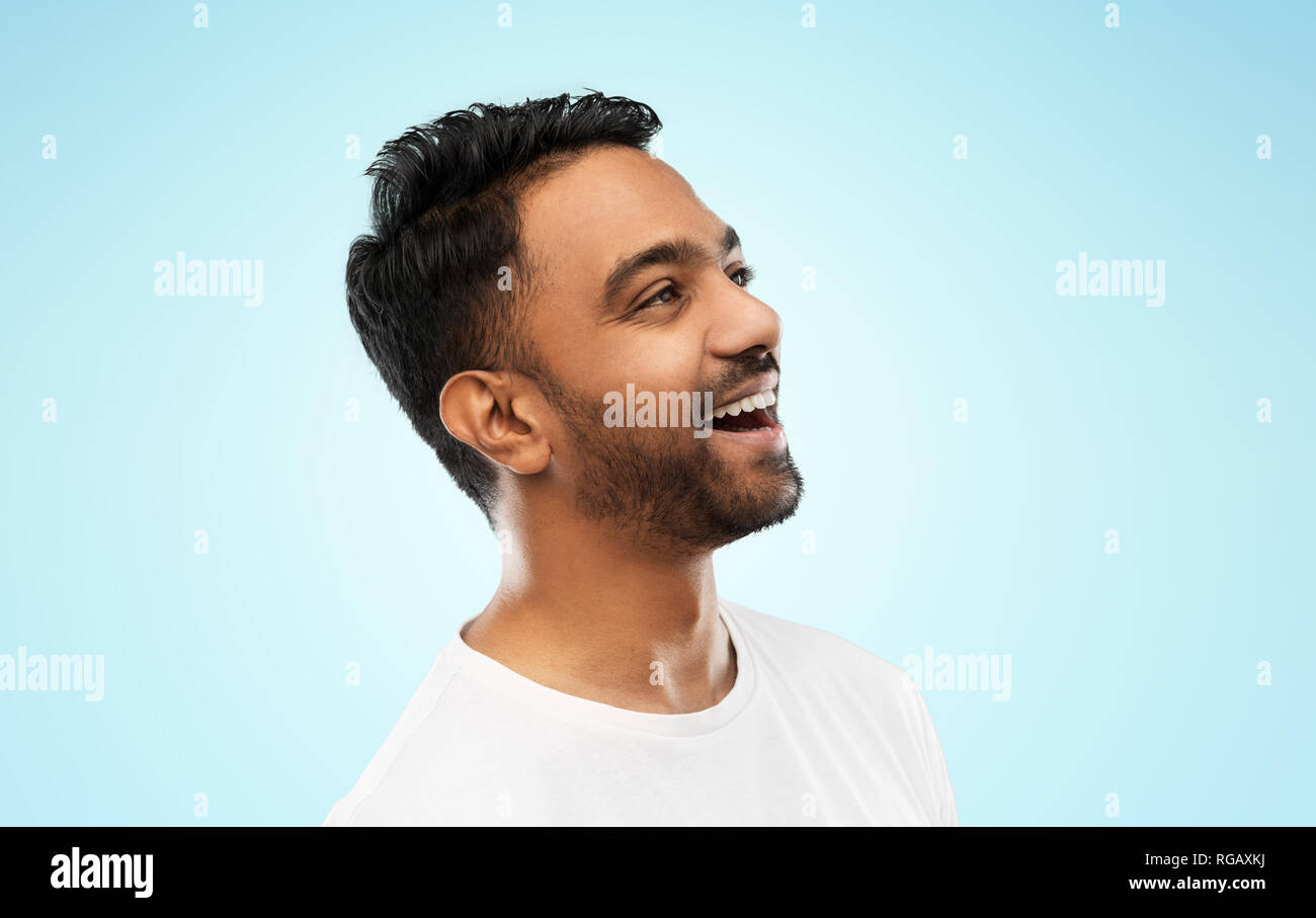Giovani ridere uomo indiano su sfondo grigio Foto Stock
