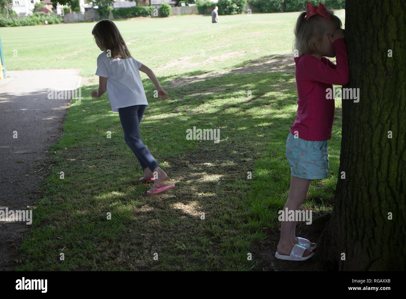 Due ragazze di giocare a nascondino in un parco in estate Foto Stock