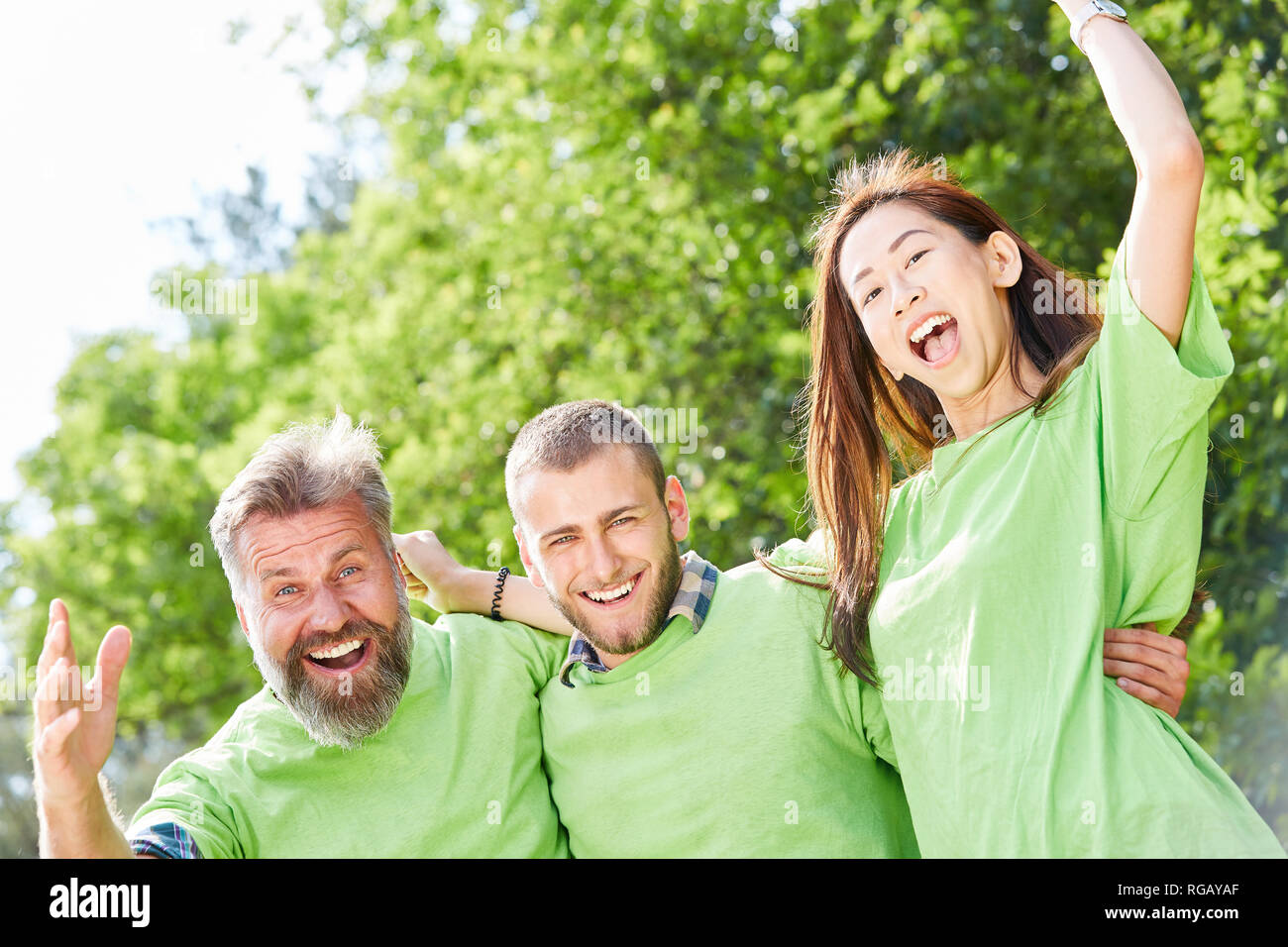 Tre giovani come attivisti con la maglia verde con entusiasmo celebrare un successo Foto Stock