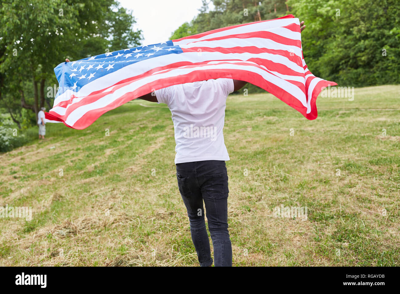 Lo studente è in esecuzione con sventola bandiera degli Stati Uniti attraverso un parco come un segno di patriottismo Foto Stock