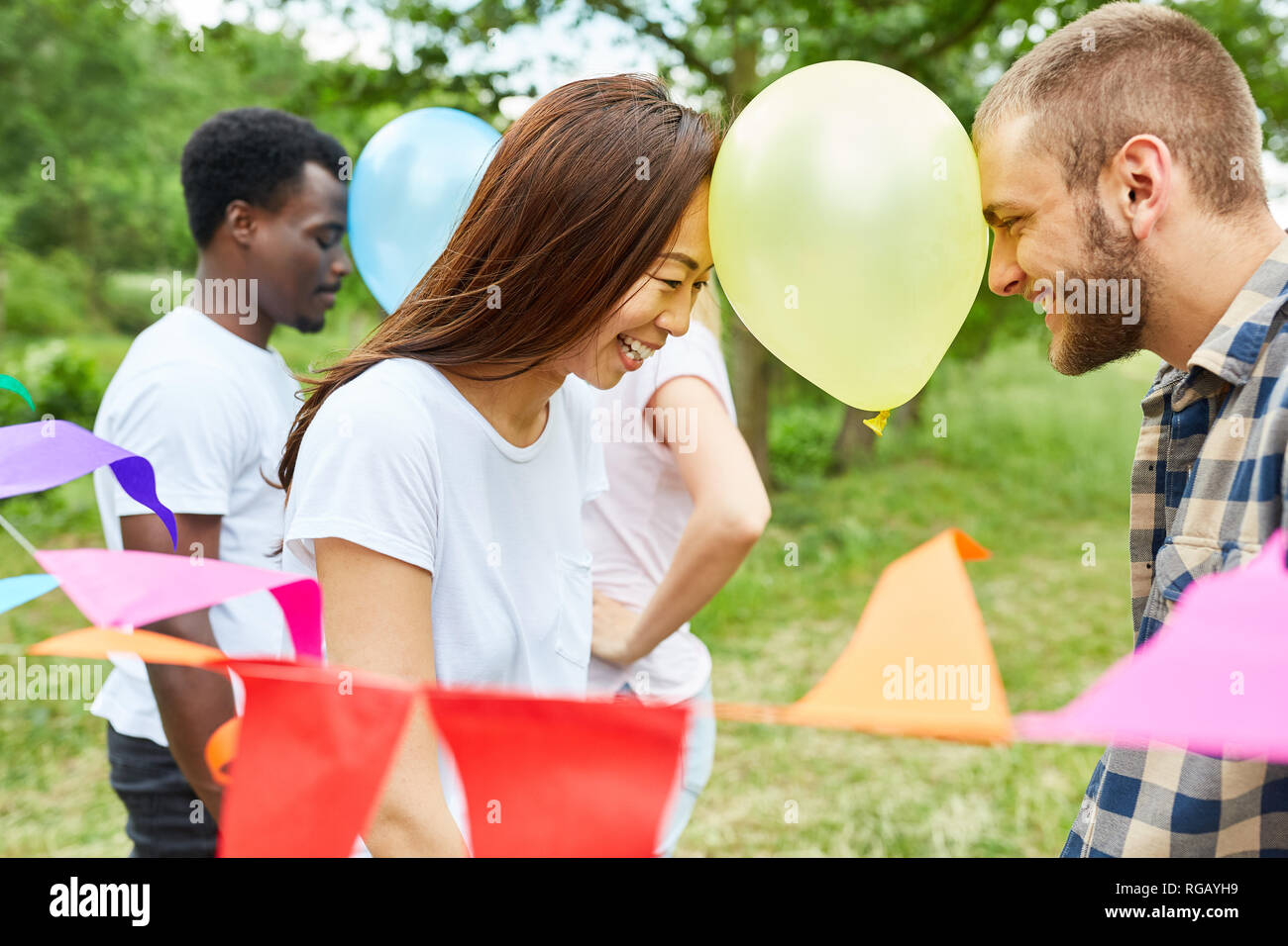 Giovane coppia multiculturale è il bilanciamento di un palloncino a un party game Foto Stock