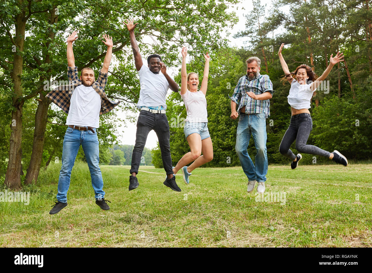 Felice gruppo multiculturale di persone durante il salto nella natura Foto Stock