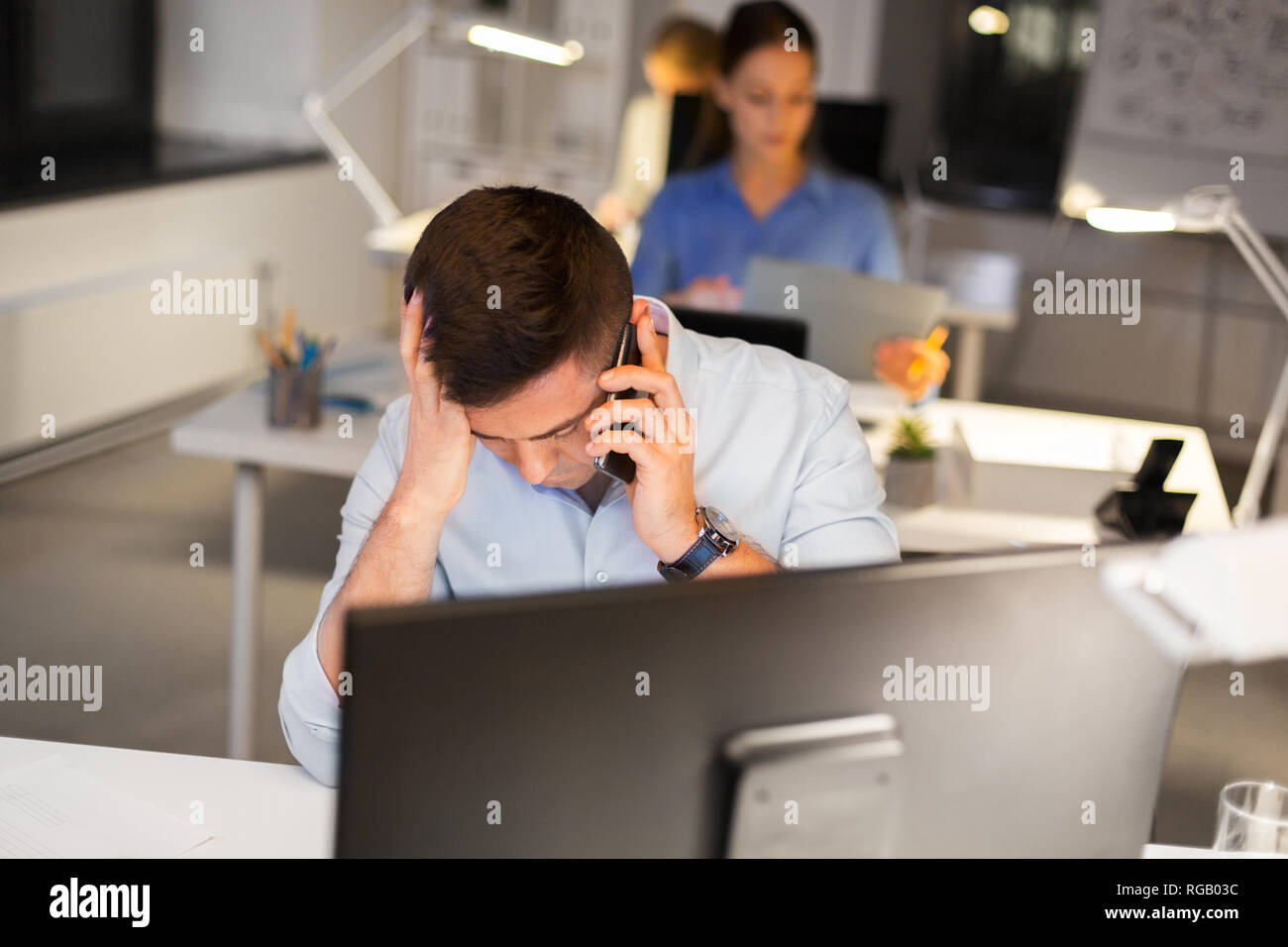 Ha sottolineato l'uomo chiamando sullo smartphone di notte office Foto Stock