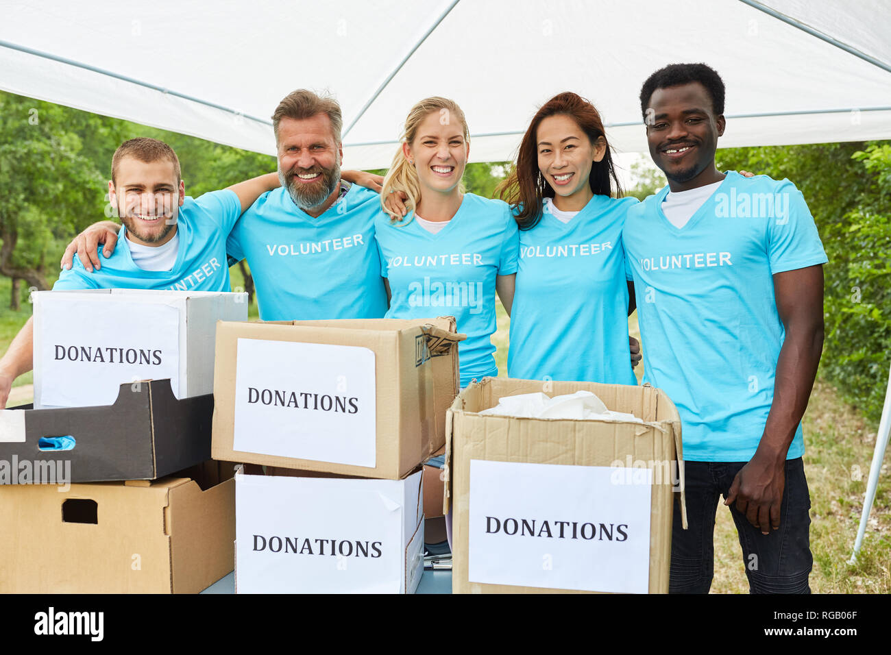 Persone nel team come volontari in una raccolta di fondi con scatole di donazione Foto Stock