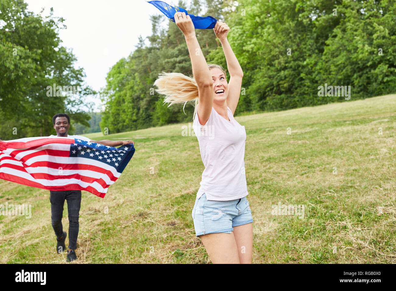 Studente americano è in esecuzione con la bandiera nazionale nel parco con una giovane donna Foto Stock