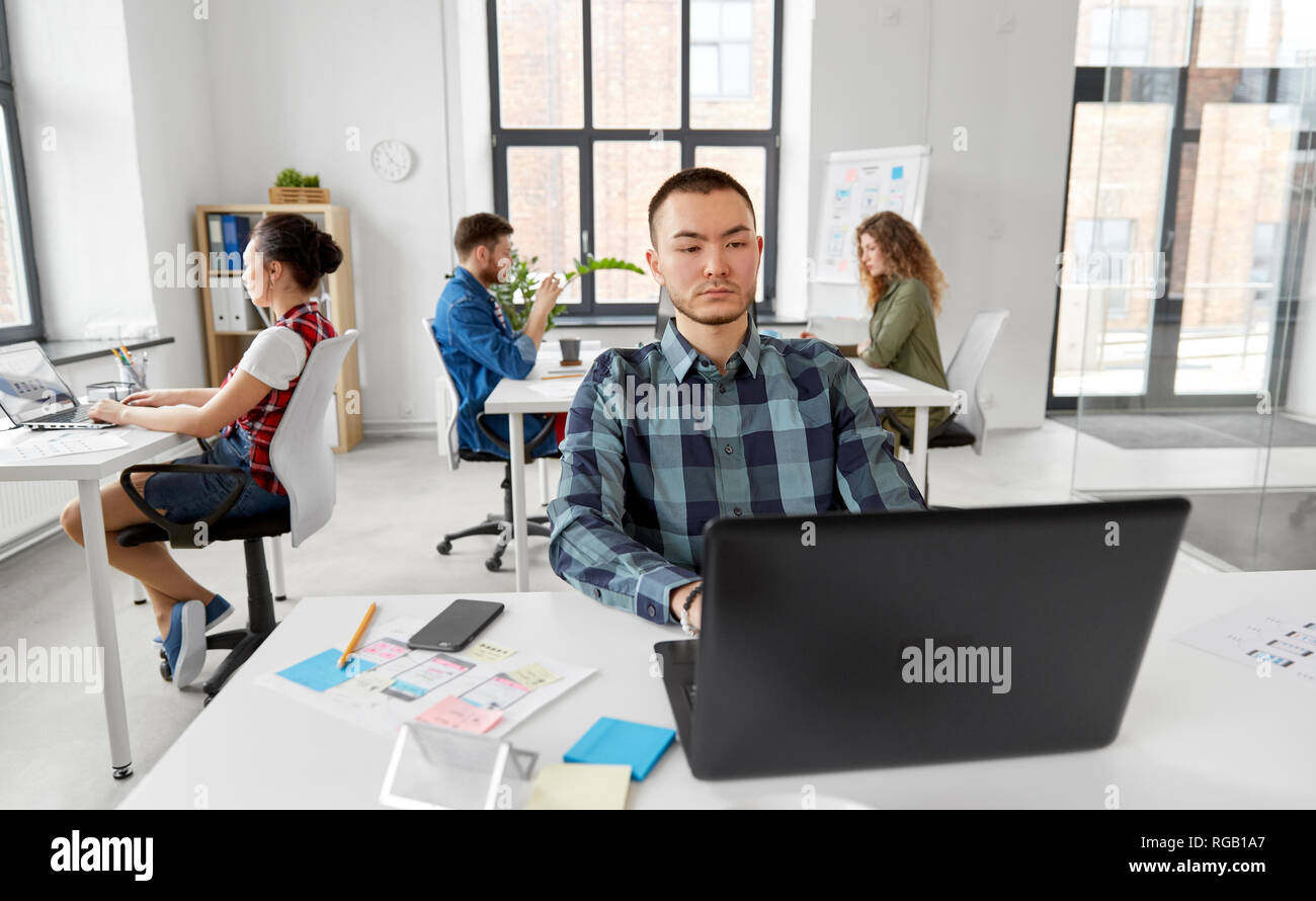 Uomo creativo con il computer portatile lavorando in ufficio Foto Stock