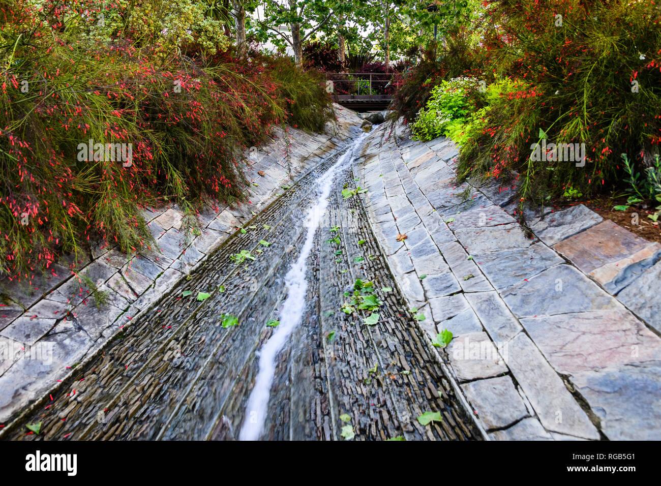 Giugno 8, 2018 Los Angeles / CA / STATI UNITI D'AMERICA - La lussureggiante vegetazione che circonda un torrente di acqua che fluisce attraverso il Robert Irwin del giardino centrale presso il Getty Center; Foto Stock