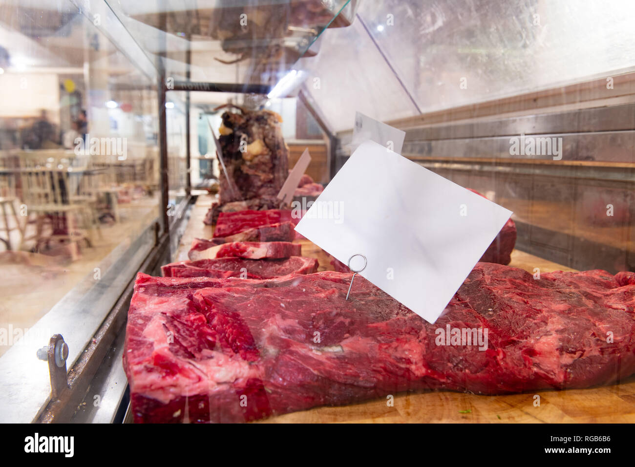 Vista laterale di materie di carni bovine solido in macelleria stallo, spazio copia su bianco cartellino del prezzo Foto Stock