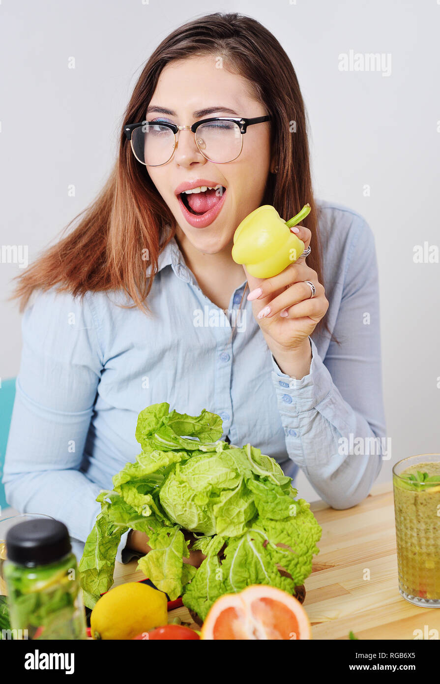 Giovane e bella ragazza con i peperoni e il cavolo nero sullo sfondo di una tabella con le verdure. Foto Stock