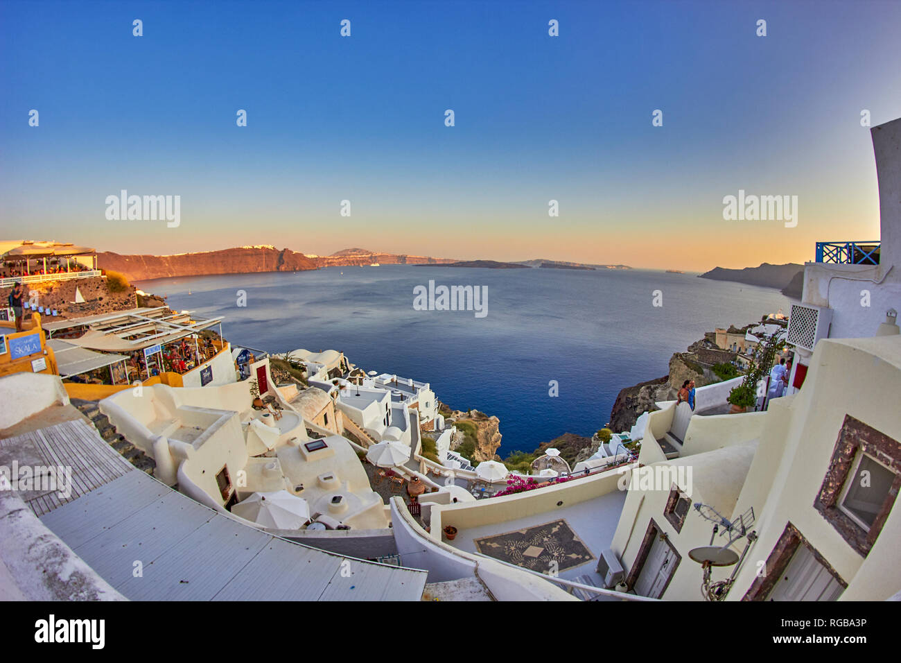 Fantastici panorami dal villaggio di Oia a Santorini Island. Tramonto idilliaco con turisti e visitatori di camminare lungo le tradizionali case greche a Oia Foto Stock