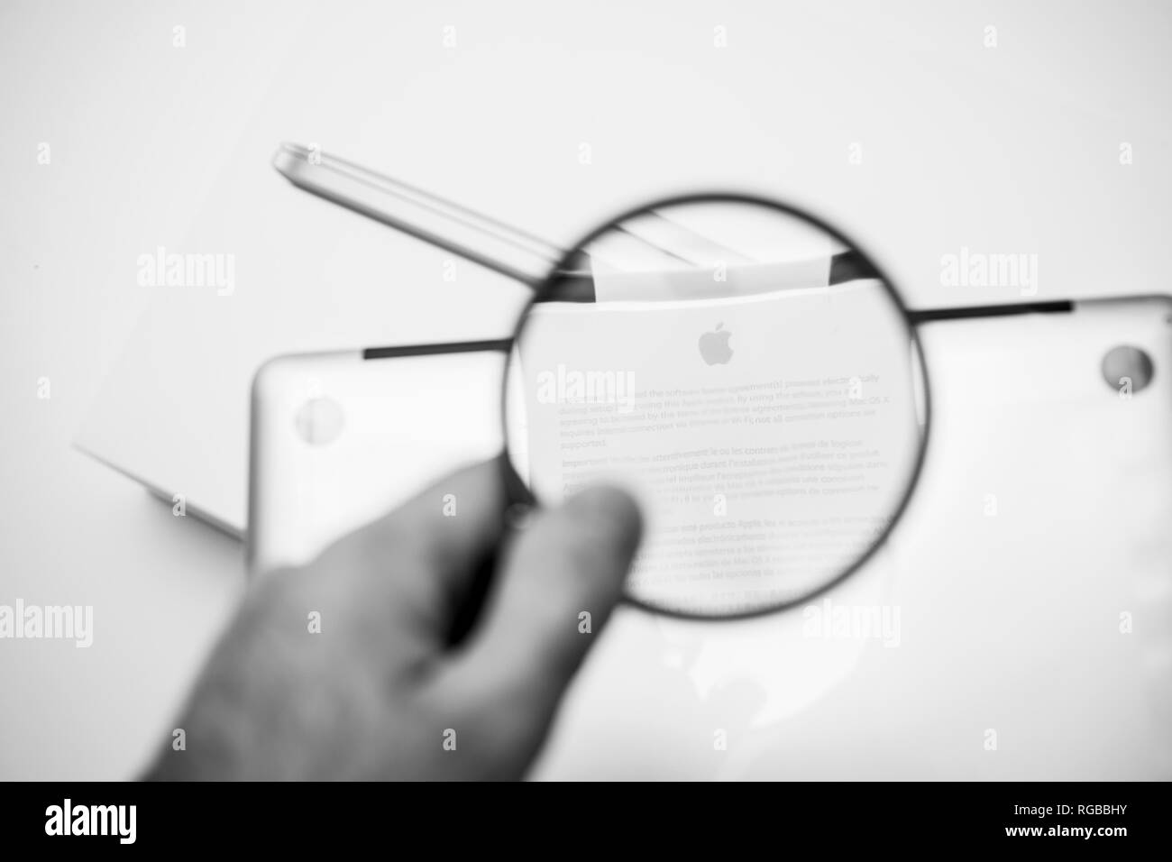 LONDON, Regno Unito - Jan 14, 2015: nuovo Apple MacBook Pro laptop computer con processori veloci e GPU unboxing con adesivo privacy e il contratto di licenza di lettura con loupe magnyfiyng vetro - bianco e nero Foto Stock