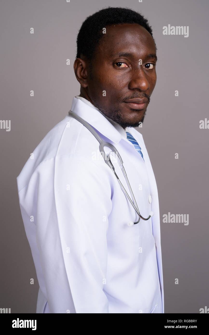 Bel giovane uomo africano medico contro uno sfondo grigio Foto Stock