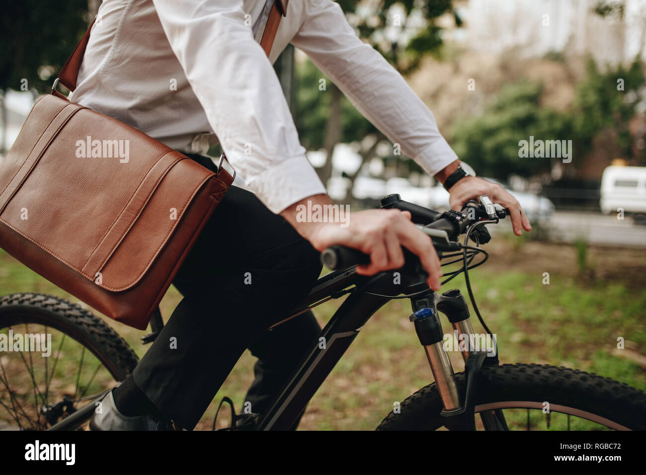Uomo che indossa una borsa da ufficio in sella ad una bicicletta. Imprenditore andando a office su una bicicletta. Foto Stock