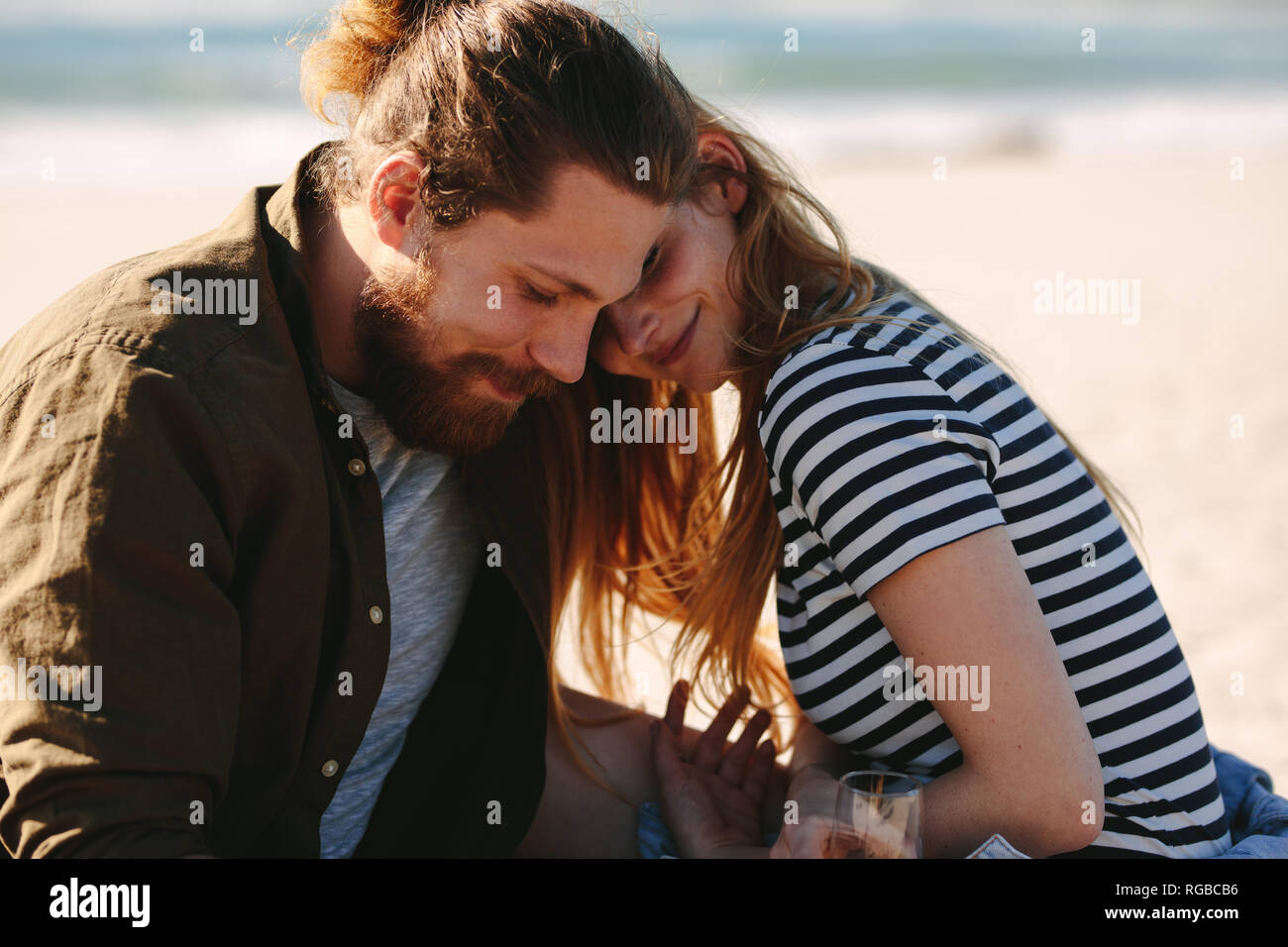 Coppia romantica rilassante sulla spiaggia. L uomo e la donna in amore seduti sulla riva del mare con champagne. Foto Stock