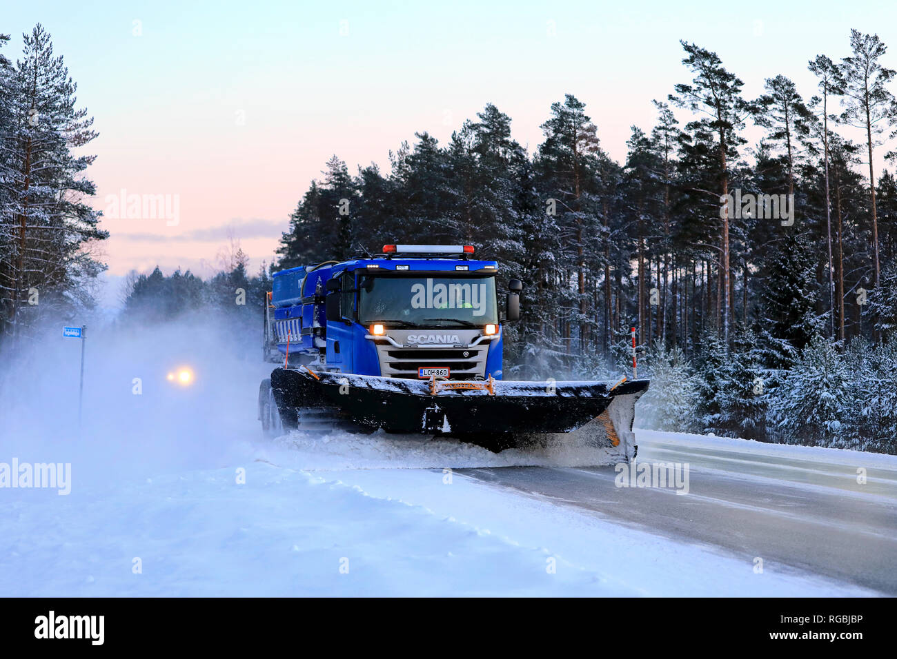 Salo, Finlandia - 18 Gennaio 2019: Blu Scania carrello equipaggiato con spartineve cancella un autostrada nevoso nel sud della Finlandia in inverno al tramonto. Foto Stock