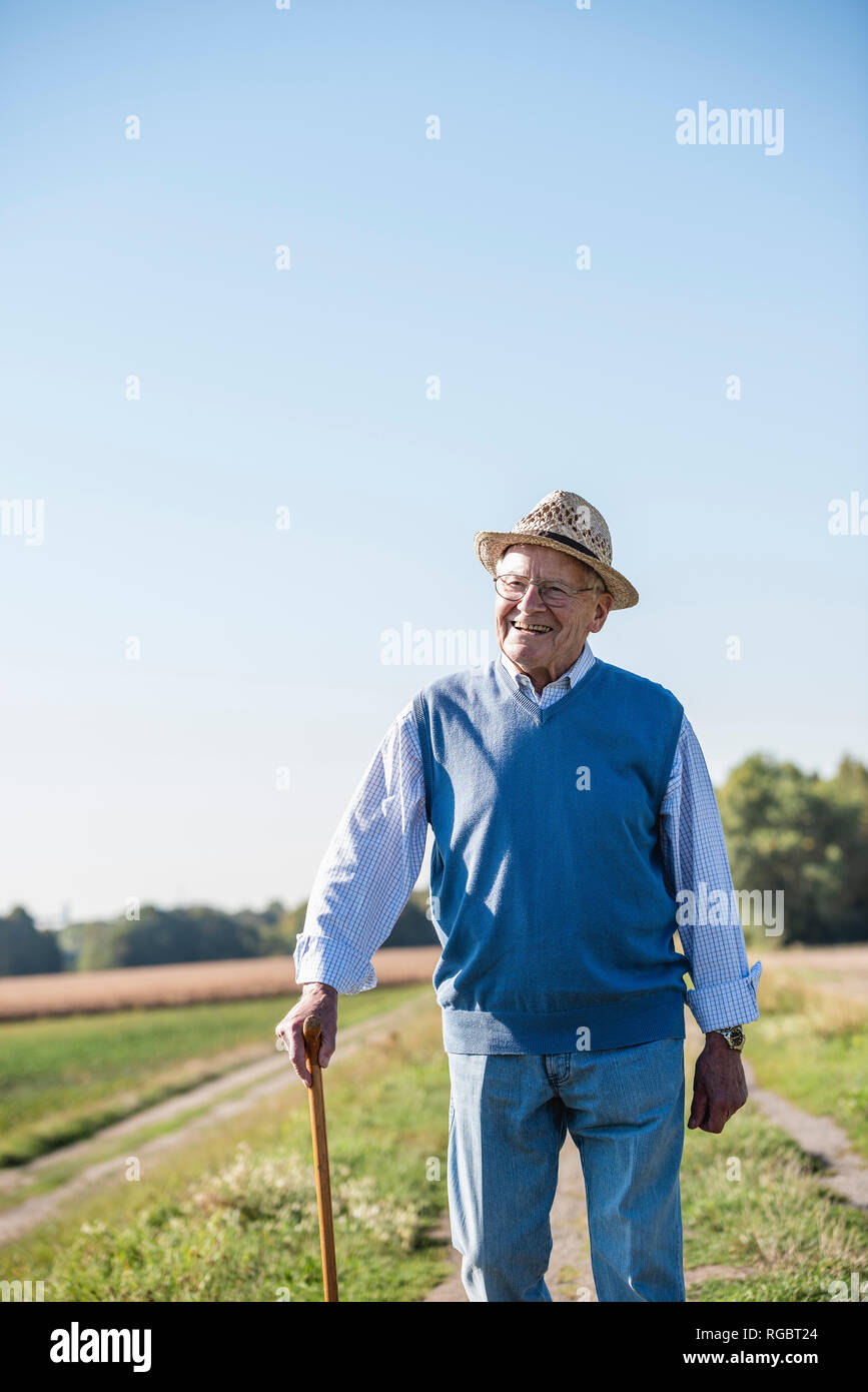 Senior uomo con un bastone da passeggio, passeggiate nei campi Foto Stock