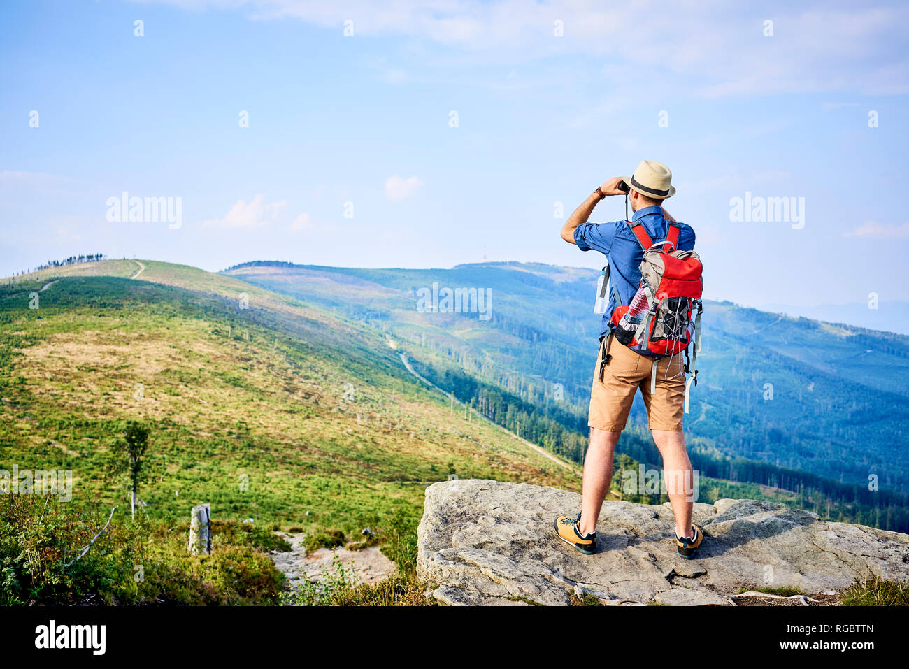 Vista posteriore dell'uomo cerca attraverso il binocolo durante il viaggio escursionistico Foto Stock