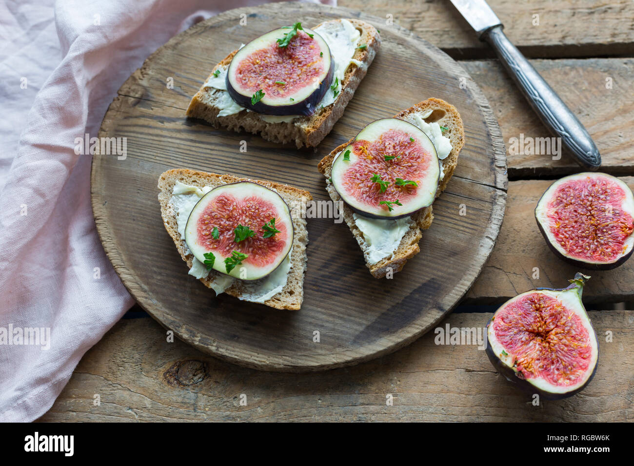 Fette di pane imburrate con spicchi di fichi sul piatto di legno Foto Stock