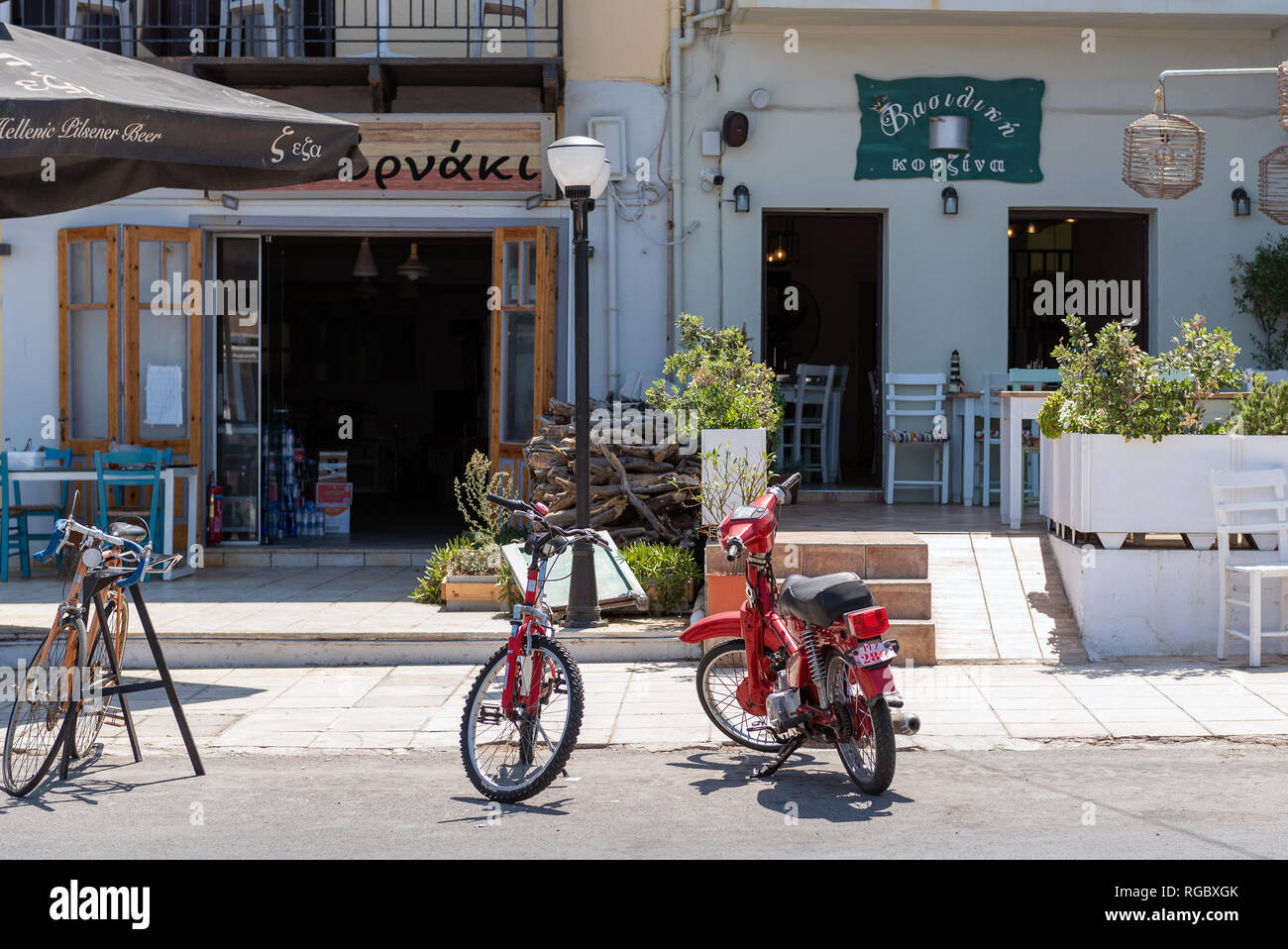 RETHYMNO, Grecia - Agosto 2018: biciclette e ciclomotori sono stare parcheggiati in prossimità tradizionale taverna greca sull isola di Creta Foto Stock