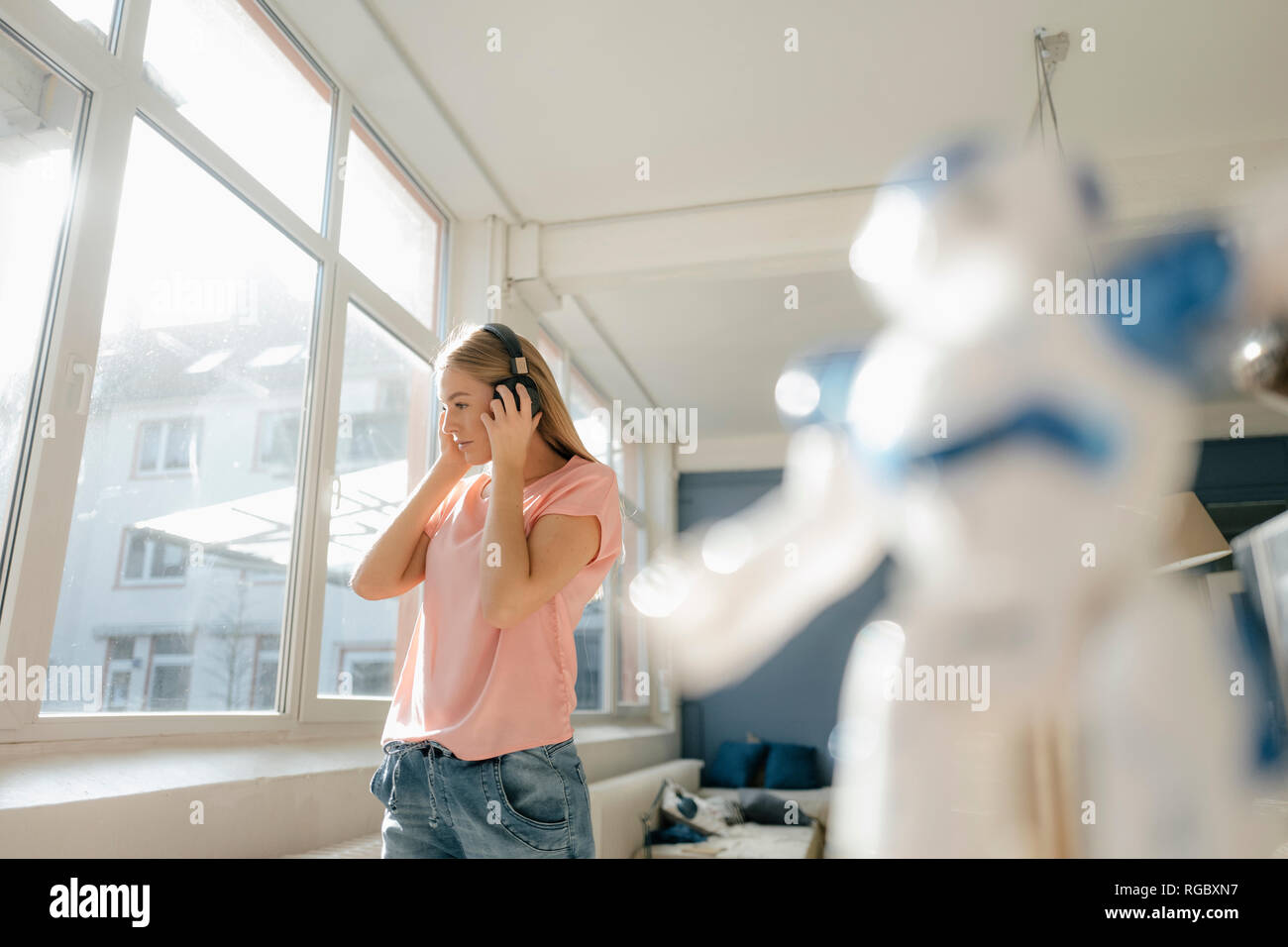 Giovane donna ascoltando musica con le cuffie a casa Foto Stock