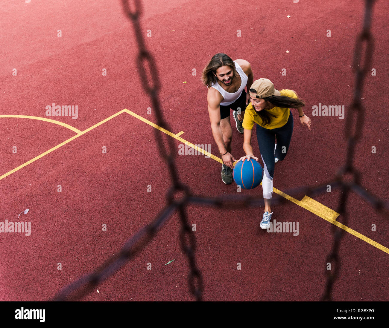 Giovane uomo e donna giocare a basket sul basket Foto Stock
