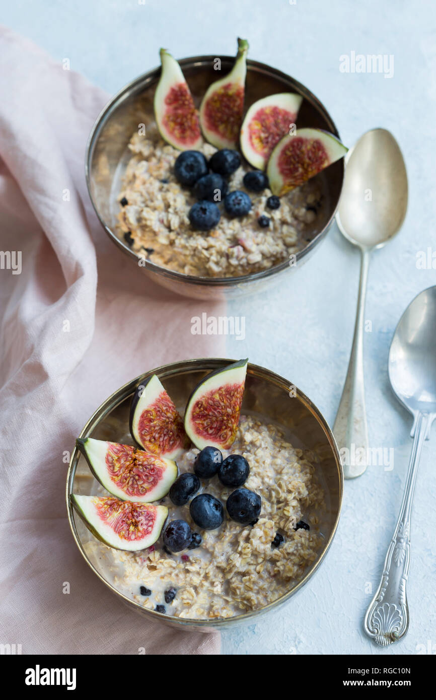 Due ciotole di porridge con spicchi di fichi, mirtilli e frutti di bosco essiccati Foto Stock