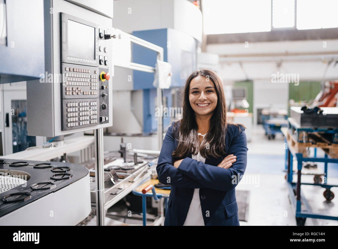 Fiducioso donna che lavorano in high tech enterprise, stando in officina in fabbrica con le braccia incrociate Foto Stock